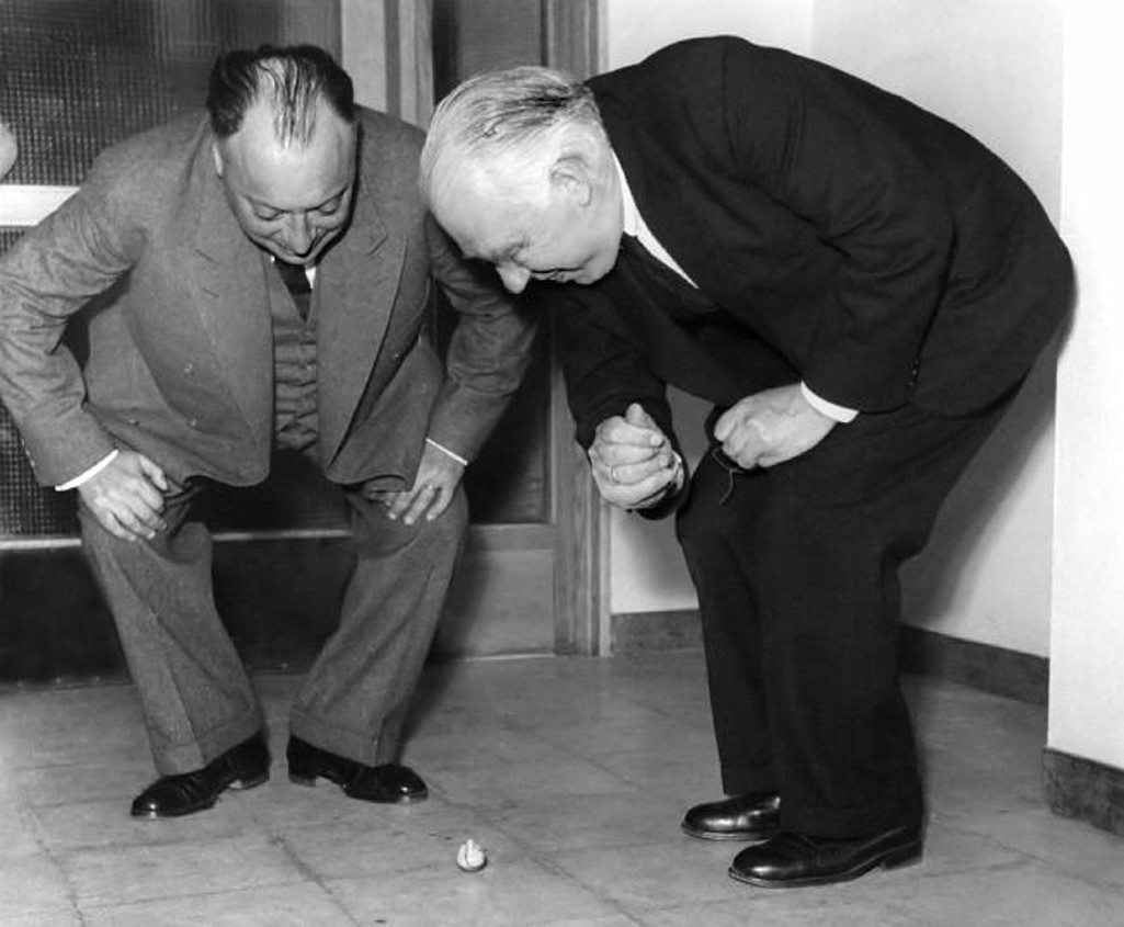 Niels Bohr und Wolfgang Pauli beugen sich über einen Stehaufkreisel